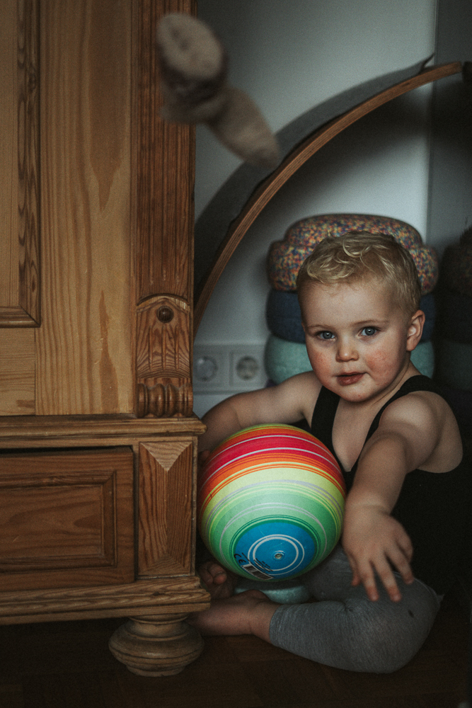 Junge knatschig mit Ball wirft Socke bei Familienshooting