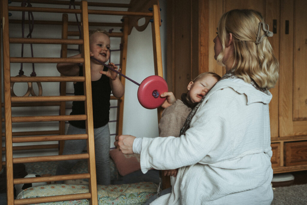 Mutter und Sohn mit schlafendem Baby spielend Homestory
