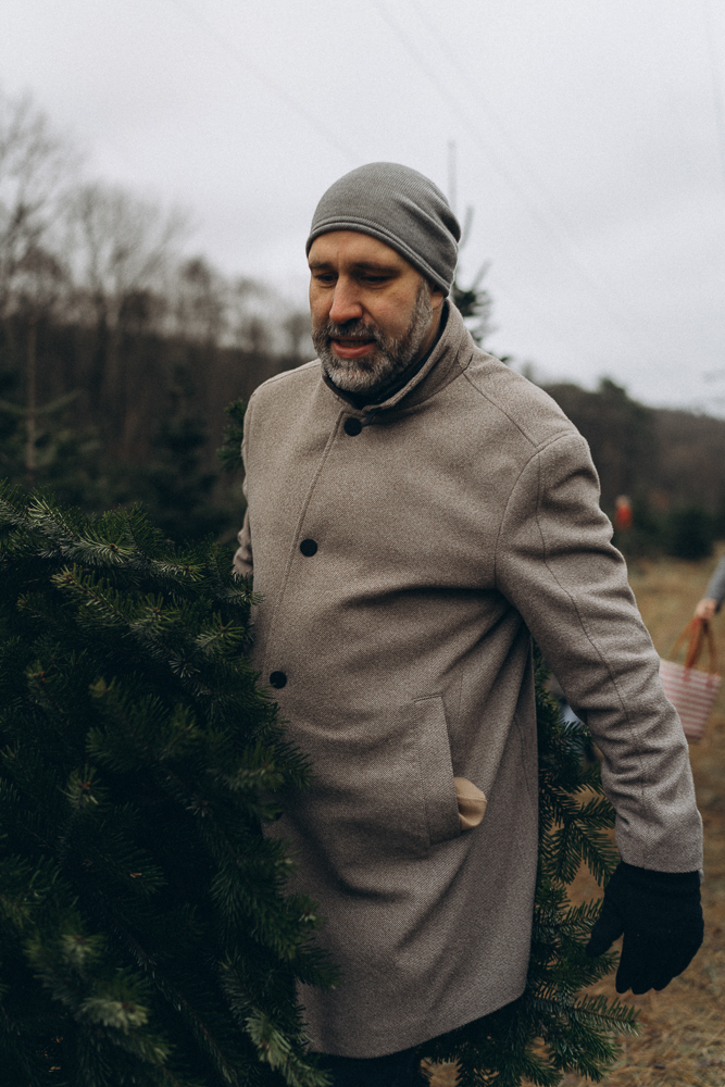 Vater trägt Tannenbaum bei Familien Outdoorshooting