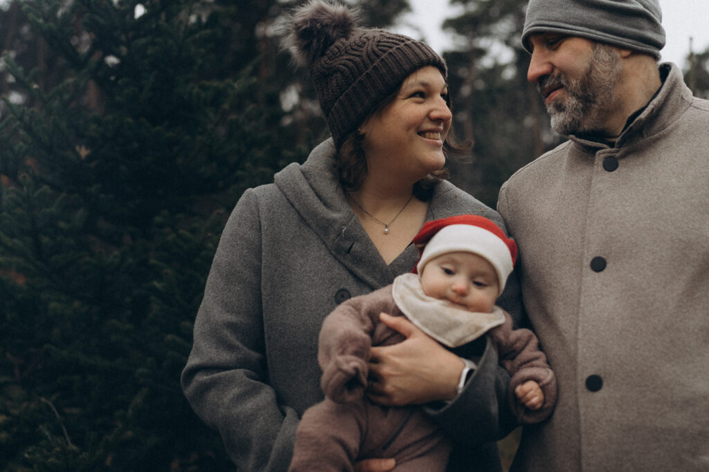 Eltern liebevolle Blicke mit Baby auf dem Arm bei Familien Outdoorshooting