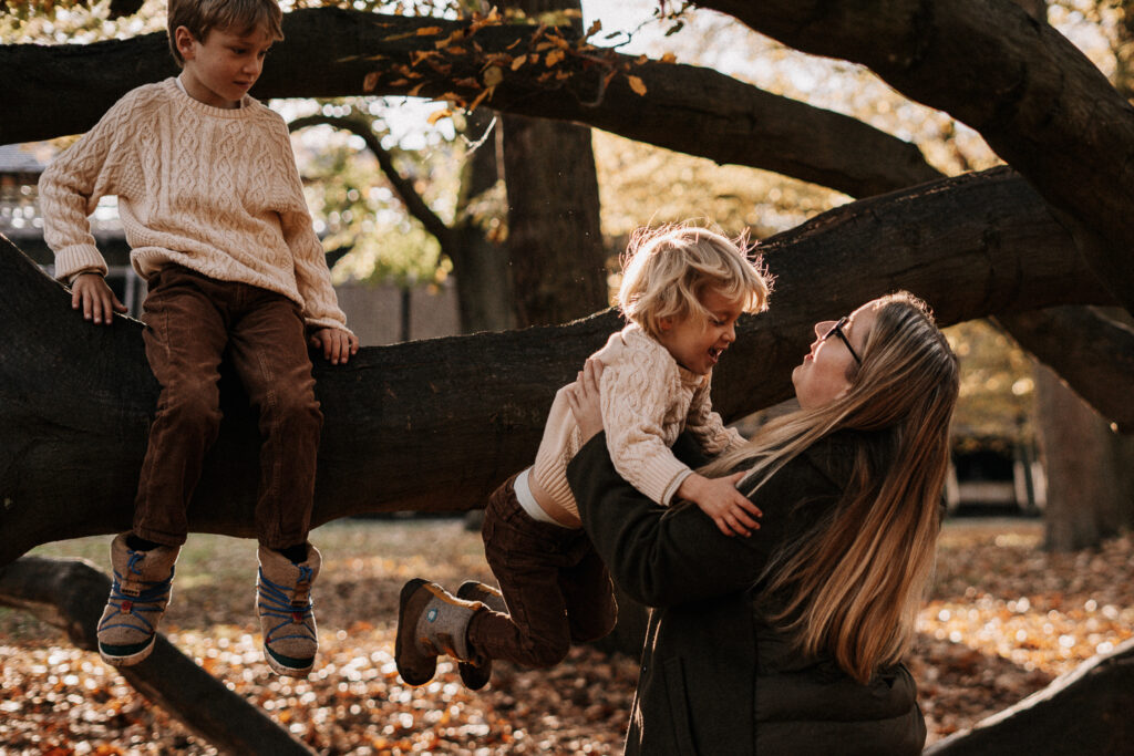 Sohn hüpft in Arme der Mutter von Baum runter fotografiert bei Familien Outdoorshooting
