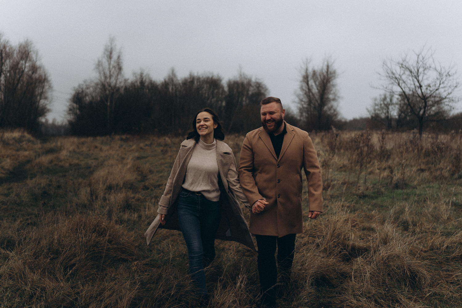 Mann und Frau laufen beim Paarshooting über eine Wiese lachend.