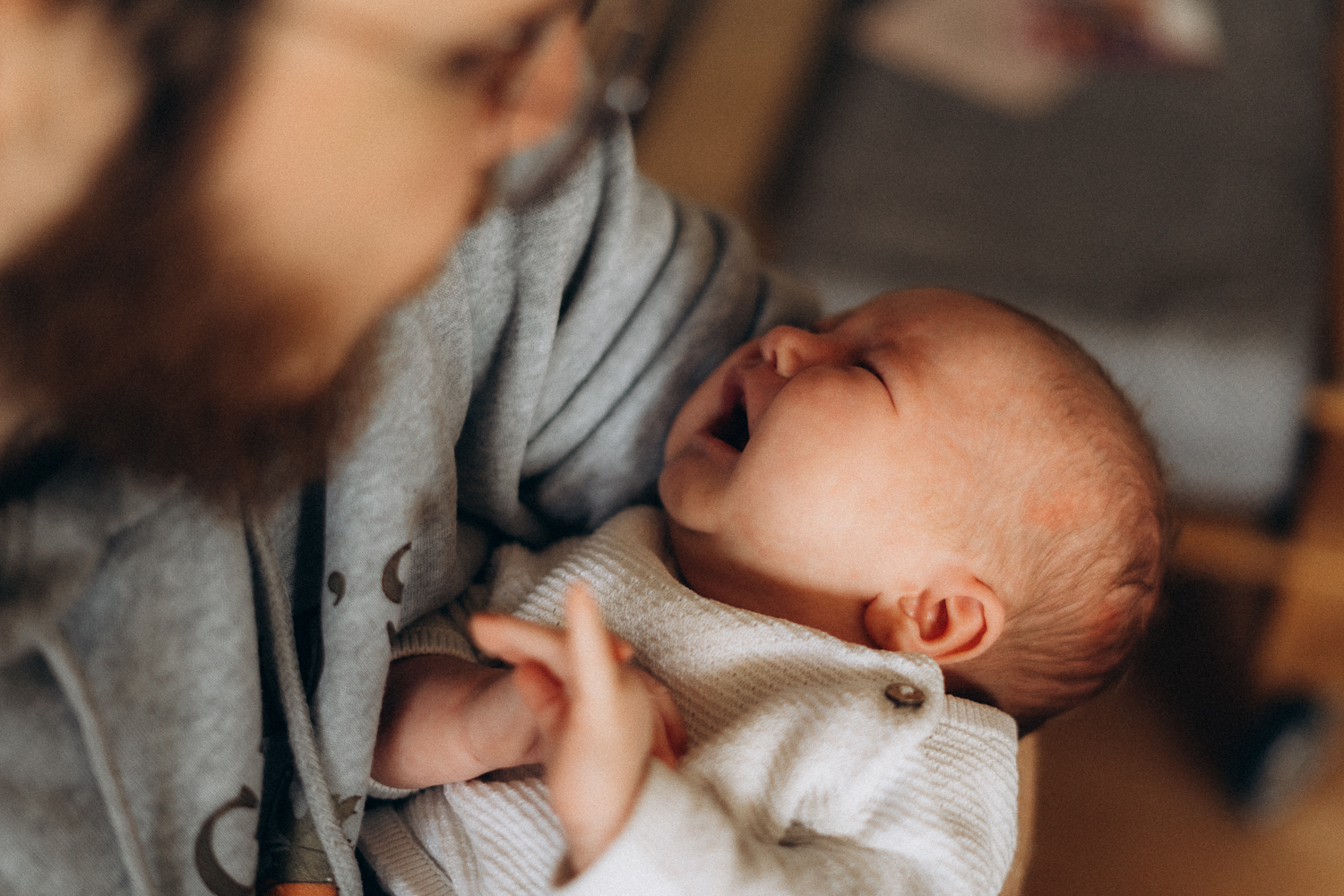 Vater mit Baby im Arm bei Neugeborenem Fotoshooting