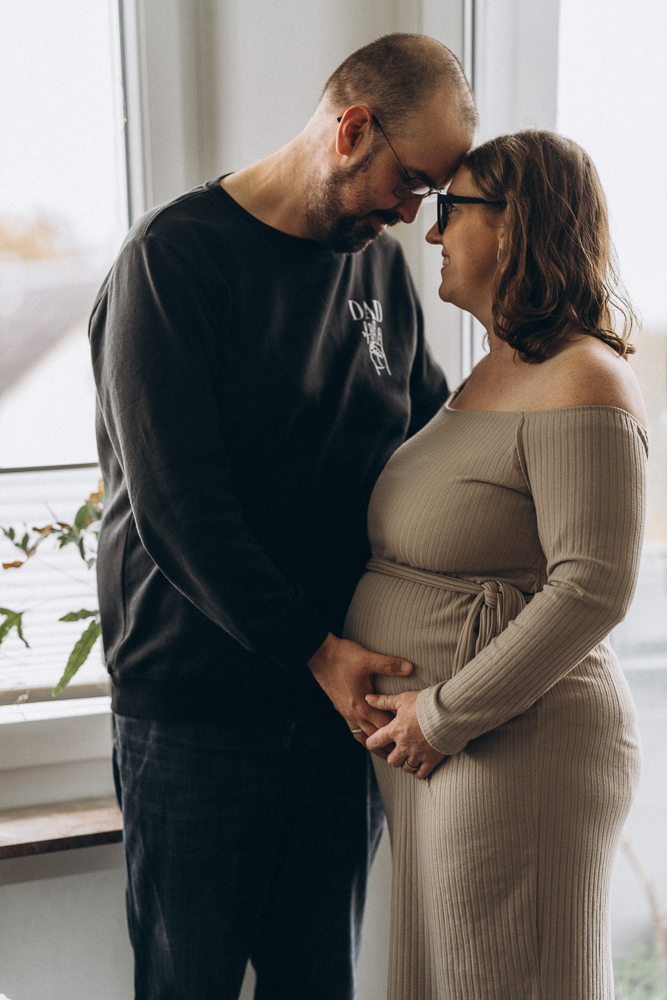 Babaybauchshooting Mama und Papa legen die Stirn sanft aneinander