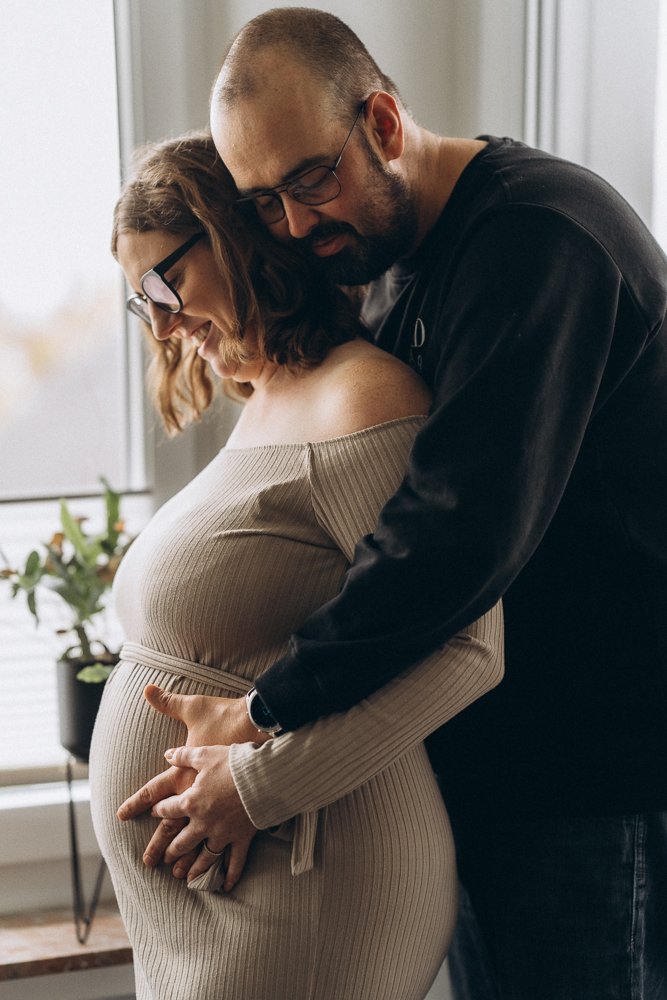 Babybauchshooting Papa umarmt Mama liebevoll